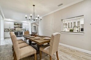 A dining area with a wooden table, beige upholstered chairs, and a chandelier.