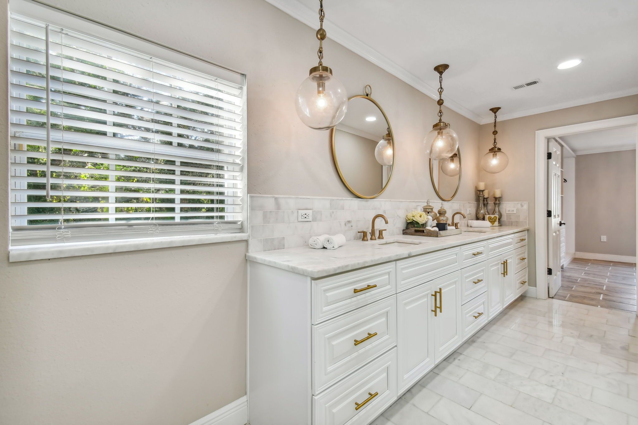 A modern bathroom with a large vanity, a mirror, and three pendant lights.