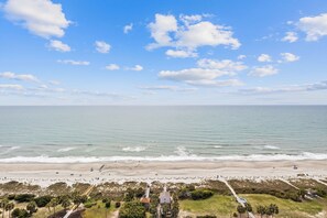 Eine Küstenansicht mit Strand, Meer und einigen Gebäuden.