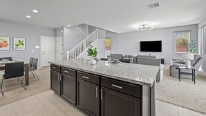 A modern kitchen with dark cabinets, a granite countertop, and a staircase leading to another level. - The Great Las Vegas Escape 4 bed 2.5 bath (Las Vegas)