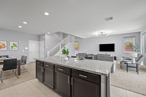 A modern kitchen with dark cabinets, a granite countertop, and a staircase leading to another level. - The Great Las Vegas Escape 4 bed 2.5 bath (Las Vegas)