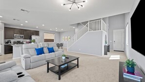 A modern living room with a gray sofa, a coffee table, and a staircase leading to an upper floor. - The Great Las Vegas Escape 4 bed 2.5 bath (Las Vegas)