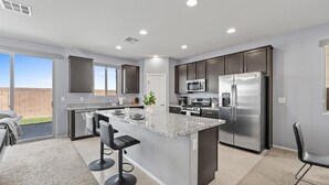 A modern kitchen with a central island, stainless steel appliances, and a view to the outside. - The Great Las Vegas Escape 4 bed 2.5 bath (Las Vegas)