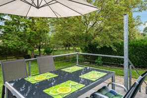 An outdoor patio with a table, chairs, and an umbrella. - Apartment for 6 Guests (70 m²) with Shared Terrace, Garden, and Wi-Fi (Kalkhorst)
