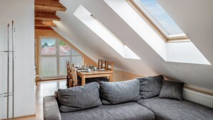 Ein Schlafzimmer im Loftsstil mit schrägem Dach, Dachfenstern, einer Essecke und einem Sofa.