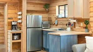 L’intérieur d’un chalet en bois comprend une cuisine équipée d’un réfrigérateur, d’un four et d’un évier.