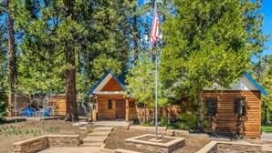 Une cabane en rondins avec un patio en pierre et un mât pour drapeau.