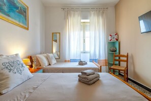 A hotel room with two beds, a wooden chair, a shelf with decorative items, and a painting on the wall. - Apartment 'Cuncordu Affitti Brevi- Alghero' with Sea View, Wi-Fi and Air Conditioning (Alghero)