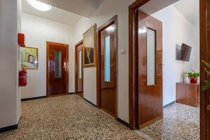A hallway with wooden doors, a fire extinguisher, and a television mounted on the wall. - Apartment 'Cuncordu Affitti Brevi- Alghero' with Sea View, Wi-Fi and Air Conditioning (Alghero)