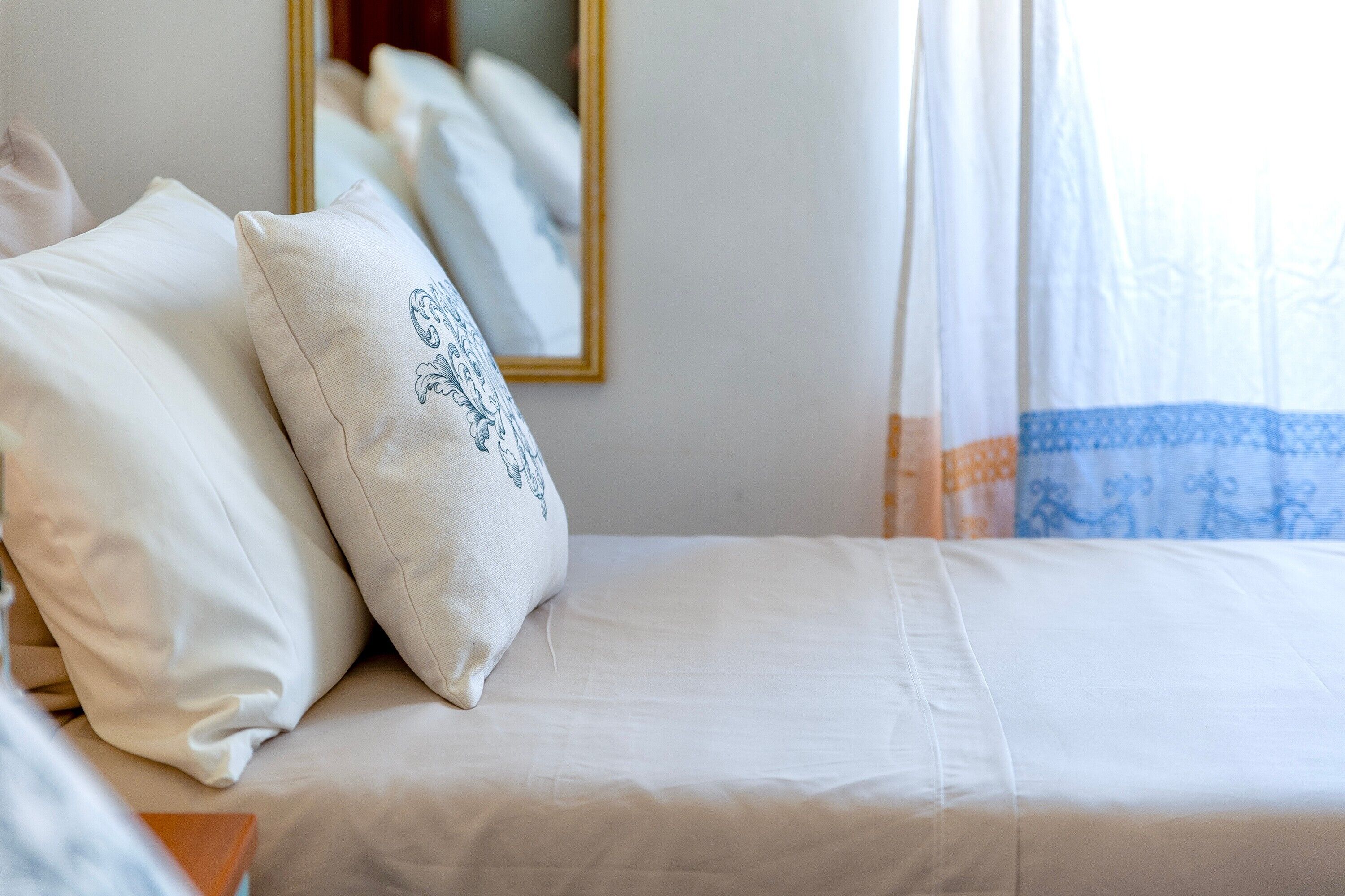 Een opgemaakt bed met witte lakens en een decoratief kussen.