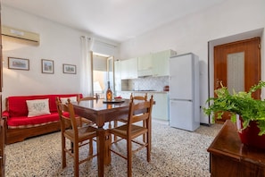 A compact kitchen with a dining area, a red sofa, and a potted plant. - Apartment 'Cuncordu Affitti Brevi- Alghero' with Sea View, Wi-Fi and Air Conditioning (Alghero)