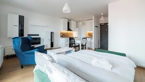 A modern hotel room with a bed, a desk, a chair, a TV, and a wardrobe. - Wilczak 16A Cosy Studio (Poznań)