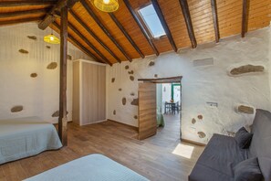 Une pièce avec un plafond en pente, des poutres en bois, un lit, un canapé et une petite table.