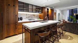 Uma cozinha moderna com armários de madeira, bancada de mármore e um espaço bar com banquetas.