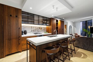 Eine moderne Küche mit Holzausstattung, einer Marmorarbeitsplatte und einer Bar mit Hockern.