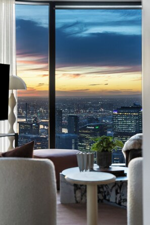 Ein modernes Zimmer mit großem Fenster und Blick auf eine Stadtlandschaft im Abenddämmerung.
