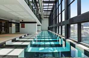 Ein moderner, überdachter Pool mit Glaswänden und Blick auf die Stadt.
