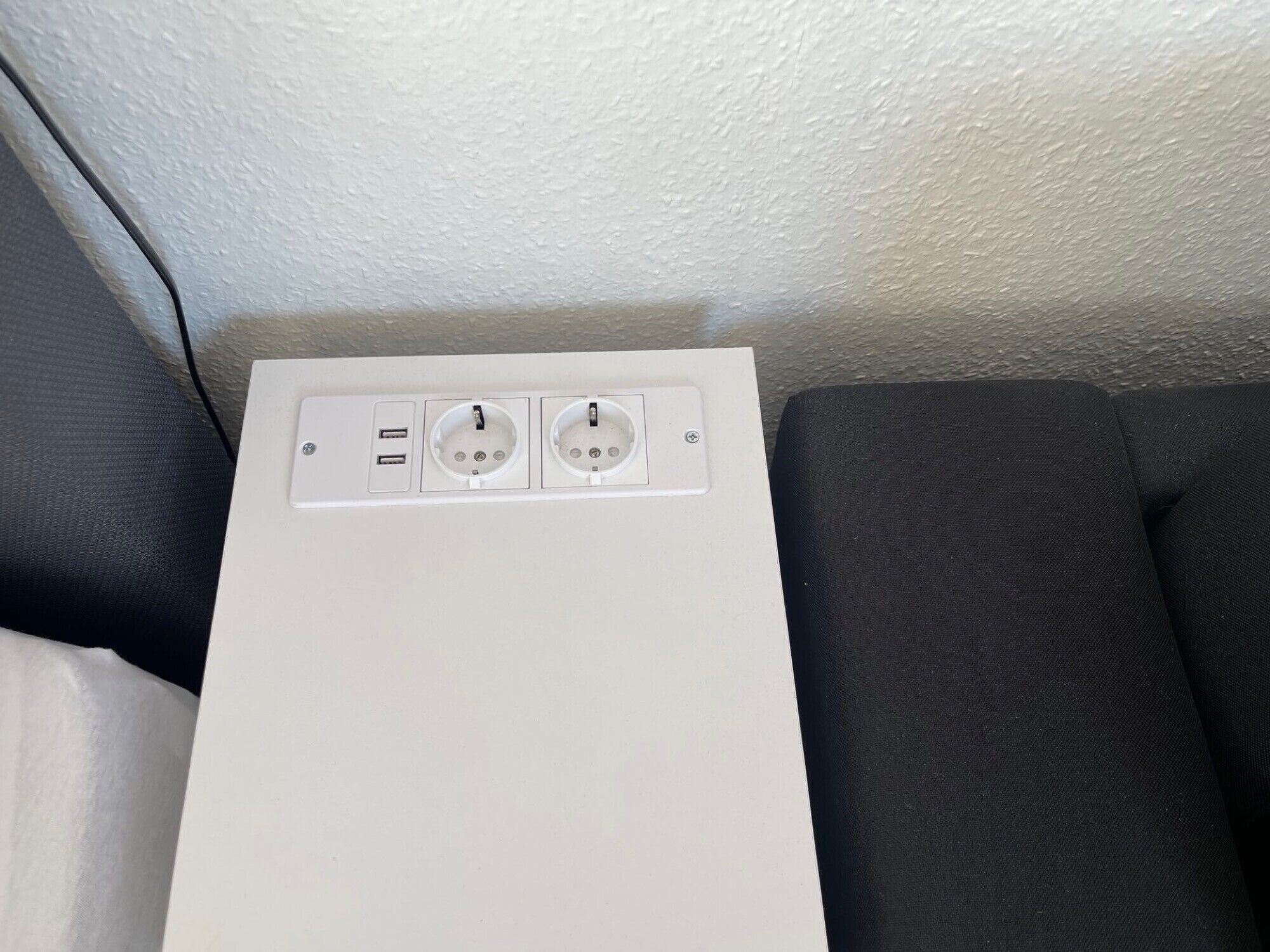 A white electrical outlet box with two USB ports and a standard electrical outlet.
