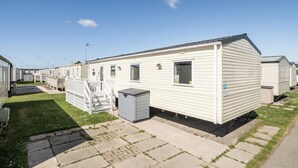 Une rangée de maisons mobiles avec un chemin pavé et une zone herbeuse.