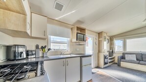Une cuisine compacte équipée d’une cuisinière à gaz, d’un grille-pain, d’un four à micro-ondes et d’un évier.