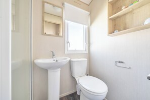 Une salle de bain avec un lavabo, des toilettes et un miroir.