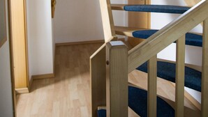 Eine Holztreppe mit Handlauf, ein blauer Sitz mit Polsterung und ein Holzboden.