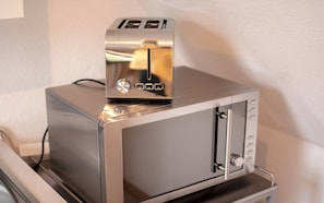 A compact, metallic toaster oven with a control panel and a single slot for bread.