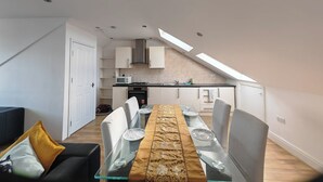 A modern apartment with a dining area, kitchen, and a loft bedroom. - Spacious Apartment Sleeps 7 near central London (Greater London)
