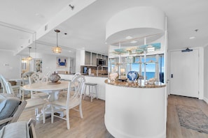 A modern kitchen with white cabinetry, a central island, and a view to the outside. - Directly on the beach, amazing views (Santa Rosa Beach)