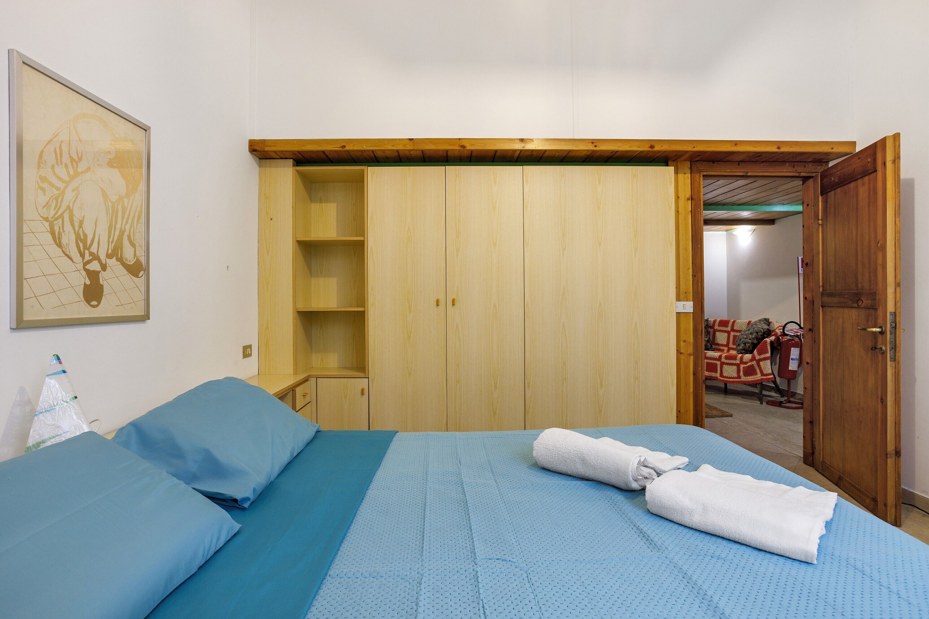 A bedroom with a bed, a wooden wardrobe, a blue mattress, and a towel.