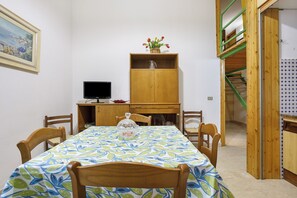 A dining area with a table, chairs, a wooden cabinet, a television, and a staircase. - Viareggio 'Burlamacco Al Mare' with Air Conditioning (Viareggio)