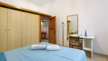 Une chambre à coucher comprenant un lit, un bureau, une chaise, une armoire et un miroir.