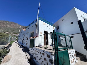 A white building with a stone facade, a green gate, and a clear blue sky.