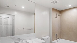 A modern bathroom with a large mirror, two sinks, a toilet, and a bathtub. - Miami World Center 2 BR heart of downtown (Miami)