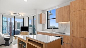 A modern kitchen with wooden cabinets, a white countertop, and a large window. - Miami World Center 2 BR heart of downtown (Miami)