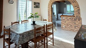 A dining area with a wooden table and chairs, a potted plant, and a brick fireplace. - Country house 20 minutes from Salers with private terrace and garden (Jaleyrac)
