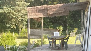 An outdoor patio with stone flooring, wicker furniture, and a wooden table with chairs.