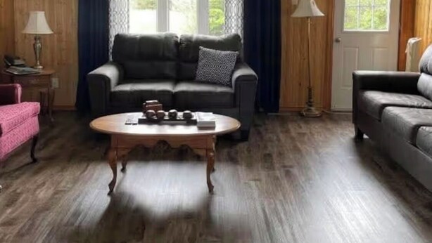 A living room with a sofa, a coffee table, and a door. - Cozy Cottage in Gros Morne - Cow Head, NL 
Sunset Lodging - Pet Friendly! (Cow Head)