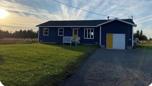 A single-story house with a front porch, a garage, and a well-maintained lawn. - Cozy Cottage in Gros Morne - Cow Head, NL 
Sunset Lodging - Pet Friendly! (Cow Head)