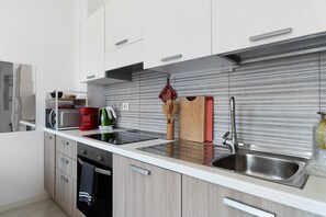 Een moderne keuken met witte kasten, een roestvrijstalen spoelbak en een magnetron.