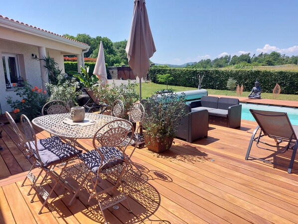 A wooden deck with outdoor furniture, a pool, and a Buddha statue.