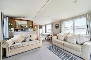 A modern living room with two sofas, a dining table, and a kitchen area.