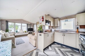 A compact living space with a kitchenette, a sofa, a television, and a dining area.