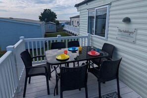 A deck with a table and chairs, a white railing, and a sign on the building.