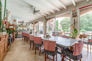 Eine geräumige Küche mit Essbereich, großen Fenstern und Deckenventilator.