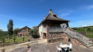 A stone house with a balcony, a staircase, and outdoor seating. - Gîte L'Oustal – Domaine Les Planes with Shared Pool, Private Terrace, and Wi-Fi (Nauviale)