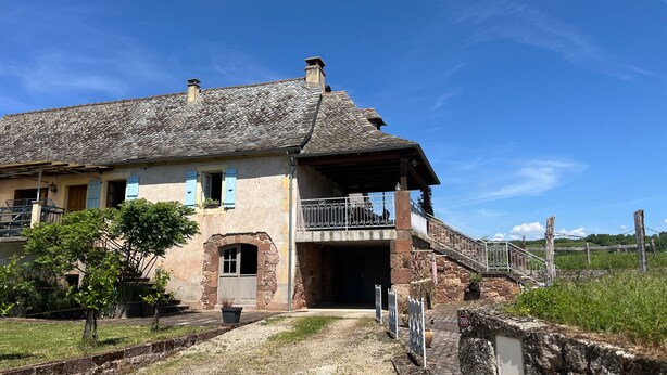 A stone house with a balcony, a gravel driveway, and a stone wall. - Gîte L'Oustal – Domaine Les Planes with Shared Pool, Private Terrace, and Wi-Fi (Nauviale)