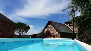 A swimming pool with a stone building in the background. - Gîte L'Oustal – Domaine Les Planes with Shared Pool, Private Terrace, and Wi-Fi (Nauviale)