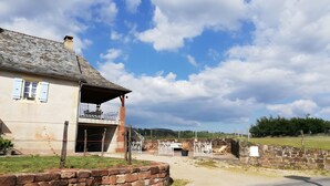 A stone house with a balcony, a stone wall, and a clear sky. - Gîte L'Oustal – Domaine Les Planes with Shared Pool, Private Terrace, and Wi-Fi (Nauviale)