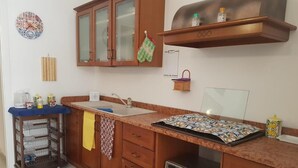Una cocina con armarios de madera, un fregadero, un microondas y una alfombra estampada.
